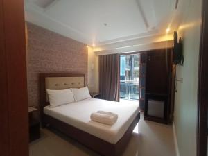 a bedroom with a white bed with a window at Panglao Alona Suites in Bolod +4 photos