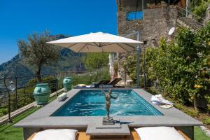 a swimming pool with an umbrella and a statue at YourHome - Casa Ivi Positano in Positano