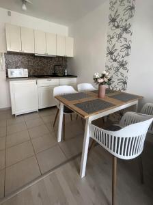 a kitchen with a wooden table and white chairs at Ada Wellness Apartman Siófok in Siófok