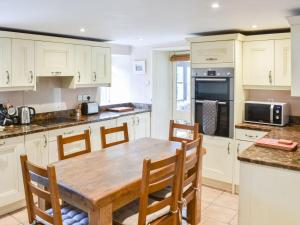 a kitchen with white cabinets and a wooden table at Red Squirrel Haven in Hawes