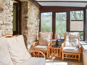 a porch with three chairs and a table and windows at Red Squirrel Haven in Hawes
