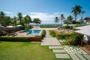 a resort yard with a swimming pool and the ocean at Tropical Beach in Porto Seguro