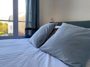 a bed with two pillows on it with a window at Cosy studio a 20 min del Arco del Triunfo en RER in Maisons-Laffitte