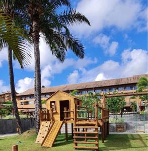 a playground in front of a building with palm trees at Flat praia dos carneiros eco resort 26 in Tamandaré