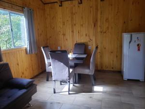 d'une salle à manger avec une table, des chaises et un réfrigérateur. dans l'établissement Cabana Azinheira, à Urubici