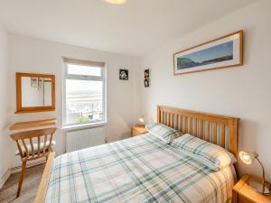 a bedroom with a bed and a chair and a window at The Mount in Appledore