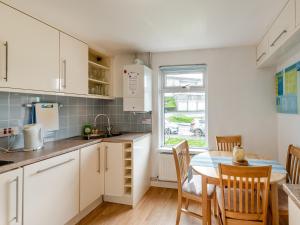 a kitchen with white cabinets and a table with chairs at The Mount in Appledore