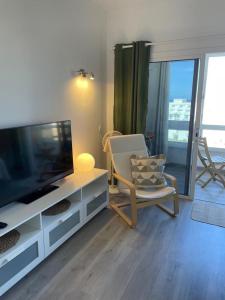 a living room with a flat screen tv and a chair at Ocean View Sunset in Adeje