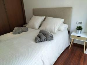 a white bed with three pillows on it at Precioso apartamento renovado in Ribeira