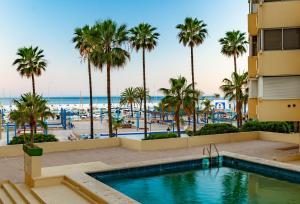 - une vue sur la plage depuis la piscine de l'hôtel bordée de palmiers dans l'établissement Appartement en front de mer, à Marbella