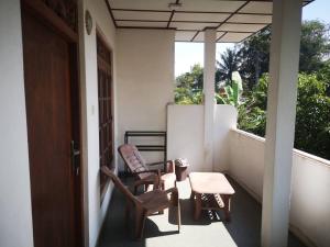 porche con 2 sillas, mesa y ventana en Sithu Guesthouse, en Bentota