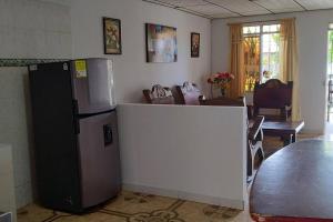 a kitchen with a refrigerator and a living room at Hermosa casa familiar in La Tebaida