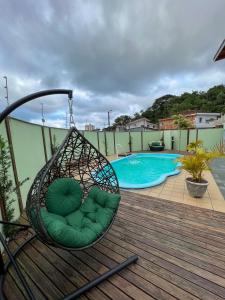 a swing on a deck next to a swimming pool at Vila Itanhaém in Itanhaém