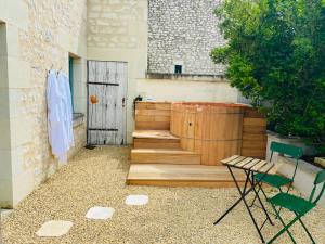 une terrasse avec une baignoire, deux chaises et un banc dans l'établissement Gîte verveine bain nordique jacuzzi l écrin de verdure chinon, à Ligré