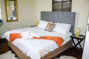 a bedroom with a large white bed with an orange blanket at Slee Guest House in Howick