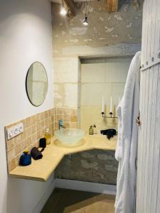 La salle de bains est pourvue d'un lavabo et d'un miroir. dans l'établissement Gîte verveine bain nordique jacuzzi l écrin de verdure chinon, à Ligré