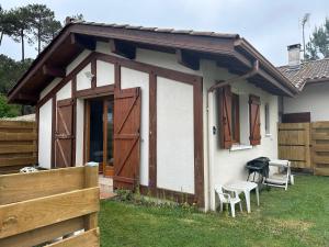 une petite maison avec des portes en bois et une clôture dans l'établissement Petite maison plein pied jardin, à Soorts-Hossegor