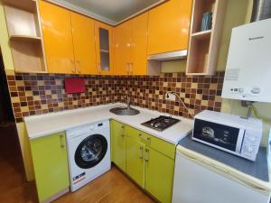 una cucina con armadi gialli e verdi e una lavatrice di Apartment on Victora Yarmoly a Kiev