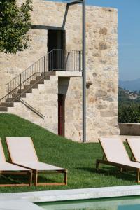 2 chaises longues sur l'herbe à côté d'un bâtiment dans l'établissement Quinta do Outeiro 1598, à Ponte da Barca