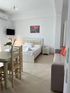 een slaapkamer met een bed, een tafel en een bank bij Garden Villa Eva in Sarandë