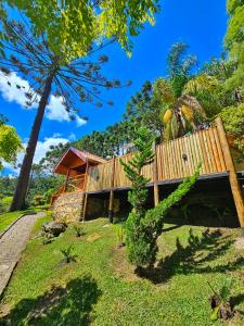 a house in the middle of a field with trees at Chalés Araucária e Manacá in São Bento do Sapucaí