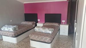 2 Betten in einem Zimmer mit rosa Wänden in der Unterkunft Apartamentos Atlas Terrassa V in Terrassa