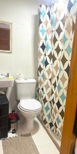 a bathroom with a toilet and a shower curtain at Quarto c/ Banheiro próximo a Praia da Barra da Tijuca in Rio de Janeiro