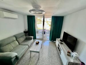 a living room with a couch and a television at Mama Yumbo in Playa del Ingles
