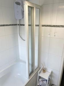 La salle de bains blanche est pourvue d'une douche avec une porte en verre. dans l'établissement Sea Side Getaway, à Portstewart