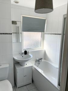 La salle de bains est pourvue d'un lavabo, de toilettes et d'une baignoire. dans l'établissement Sea Side Getaway, à Portstewart