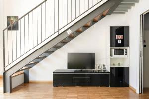 a living room with a tv under a staircase at Luxury Loft a Milano - Design esclusivo e comfort moderno in Milan