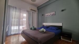 sypialnia z łóżkiem z niebieskimi poduszkami i oknem w obiekcie Koukaki near the Acropolis Stylish 2 bedroom w Atenach
