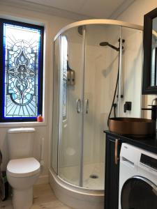 a bathroom with a shower with a toilet and a stained glass window at Tiny Home Luxury Farm Escape in Egmont Village