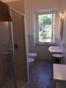 a bathroom with a toilet and a sink and a window at Villa Sant'Antonio con ampio giardino a due passi dal mare in SantʼAnna