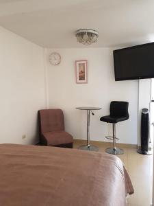 a bedroom with a bed and two chairs and a tv at Queen's Residence VIP in Tacna