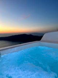 a hot tub with a sunset in the background at Esmi Suites Santorini in Imerovigli