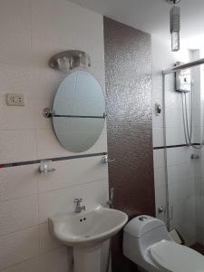 ein Badezimmer mit einem Waschbecken, einem WC und einem Spiegel in der Unterkunft Queen's Residence VIP in Tacna