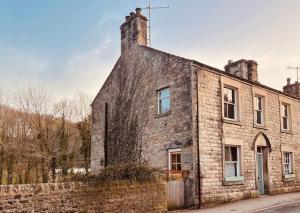 The Riverside Tailor's Retreat at Wray في Wray: منزل حجري قديم بجدار من الطوب