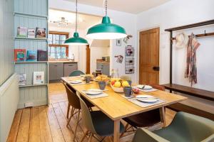 una sala da pranzo con tavolo in legno e luci verdi di The Riverside Tailor's Cottage at Wray a Wray