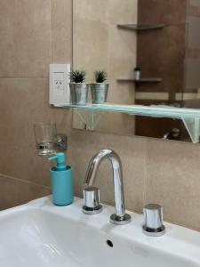 ein Waschbecken mit einem Wasserhahn und einem Spiegel in der Unterkunft Apartments Biritos in Godoy Cruz