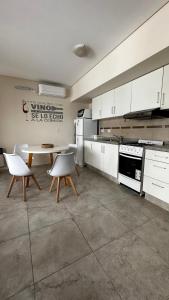 cocina con armarios blancos, mesa y sillas en Apartments Biritos en Godoy Cruz
