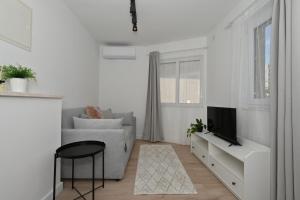 a white living room with a couch and a tv at Apartment Relax with Jacuzzi and private hot tub Split Area in Žrnovnica