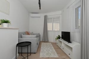 a white living room with a couch and a tv at Romantic Escape With Private Hot Tub Near Split in Žrnovnica