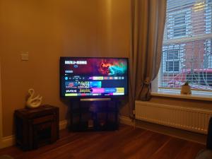 einen Flachbild-TV im Wohnzimmer mit Fenster in der Unterkunft Helens House Derry City Centre Remarkable 3-Bed in Derry Londonderry