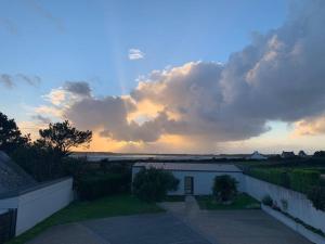 einen wolkigen Himmel mit einem Gebäude im Hof in der Unterkunft Charmante maison vue sur mer proche Carnac in Plouharnel