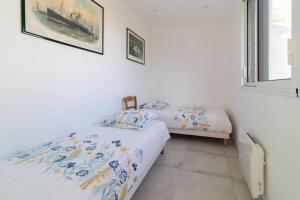 2 Einzelbetten in einem Zimmer mit weißen Wänden in der Unterkunft Charmante maison vue sur mer proche Carnac in Plouharnel