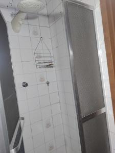 a bathroom with a shower and a white tile wall at Chalet confortável na cidade das estrelas in Santa Maria Madalena