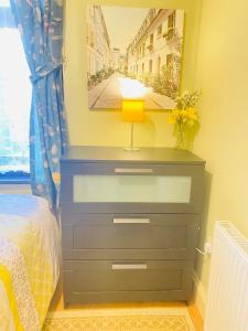 a bedroom with a blue dresser with a lamp on it at Your Cosy and Welcoming HomeStay!! in Ilford