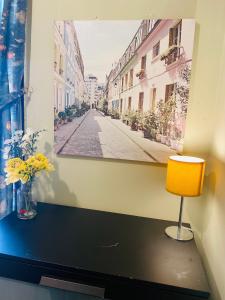a painting on a wall next to a table with a chair at Your Cosy and Welcoming HomeStay!! in Ilford