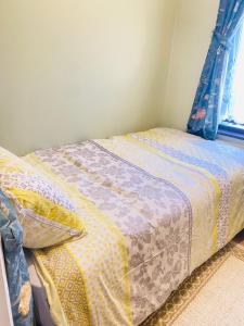 a bedroom with a bed with a quilt and a window at Your Cosy and Welcoming HomeStay!! in Ilford